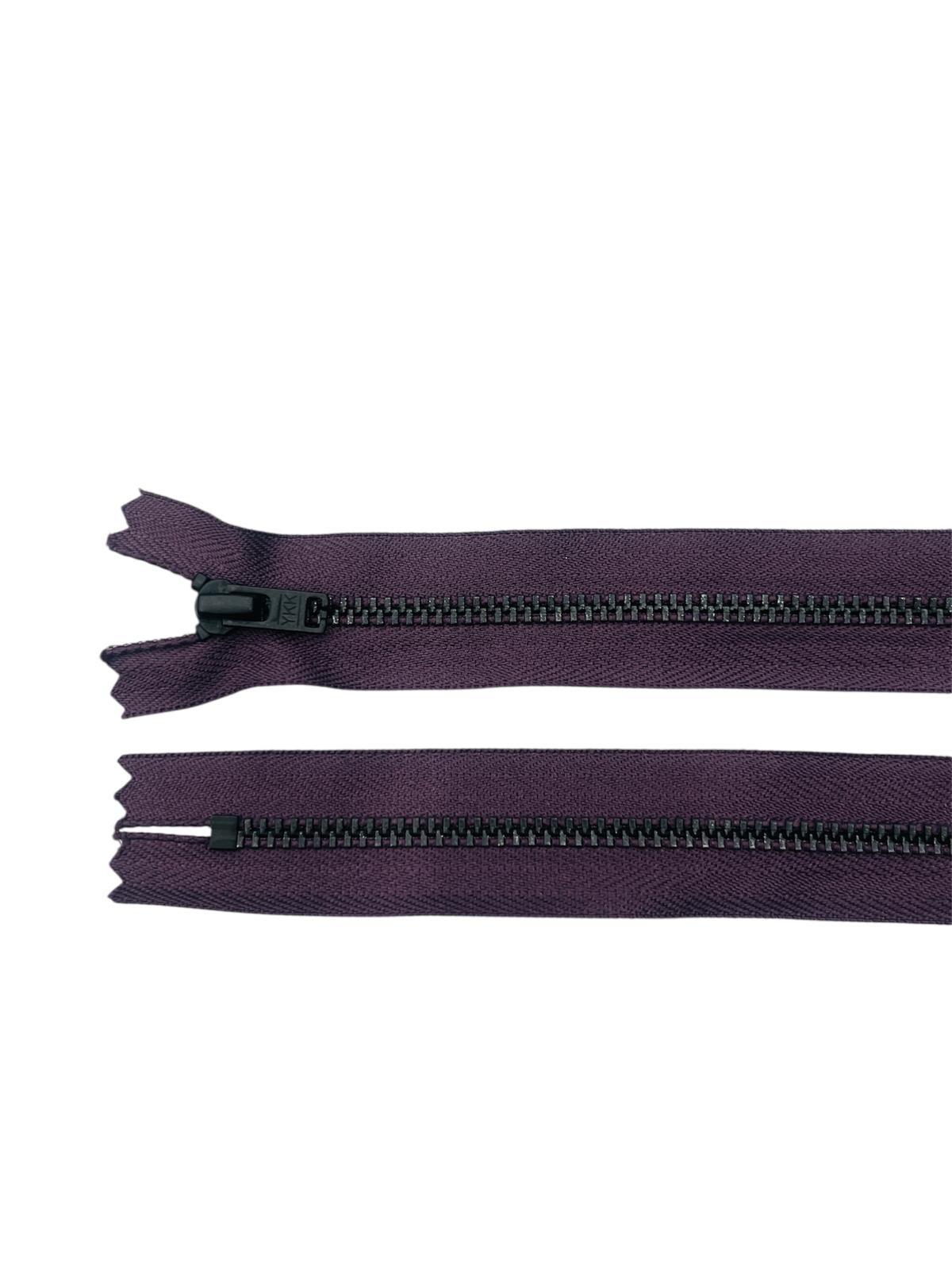 Two YKK black metal zippers on purple fabric, one open and one closed.