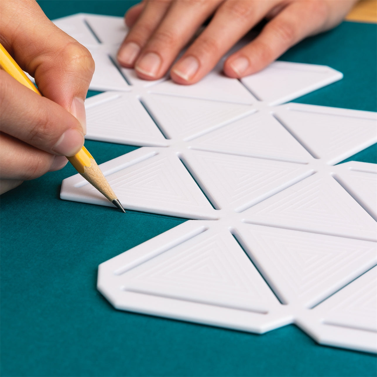 A white 3D paper gem geode template with scoring tracks is being traced with a pencil.