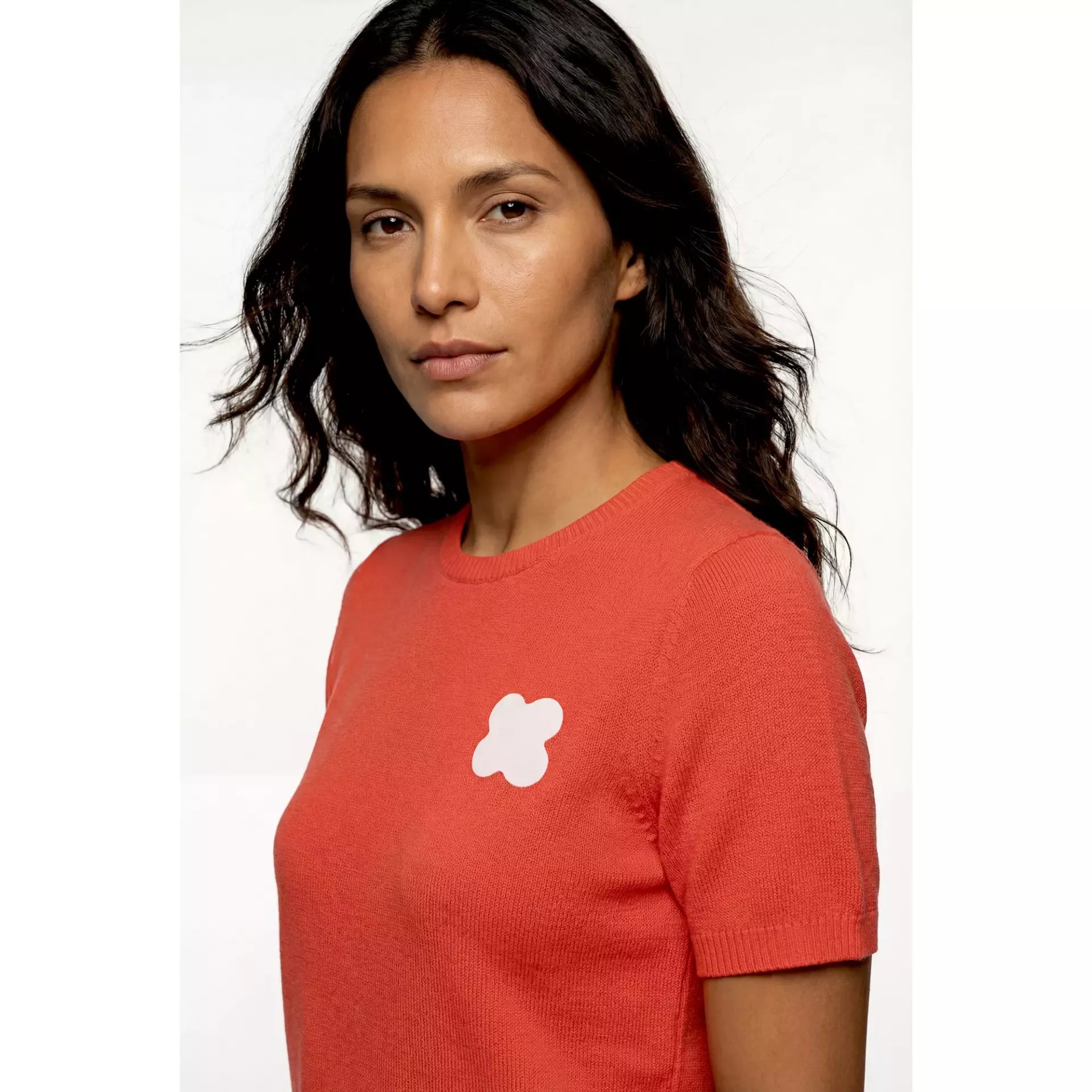 A woman wearing a red short-sleeved sweater with a white flower-shaped rub-on stretch patch.