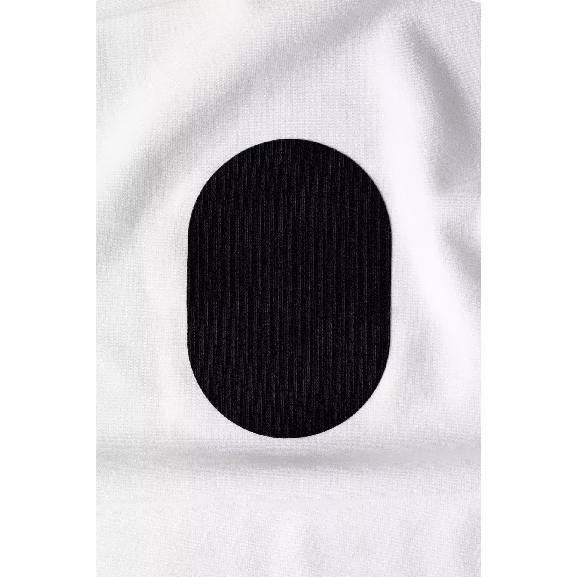 Close-up of a black oval-shaped rub-on textile repair patch on white fabric.