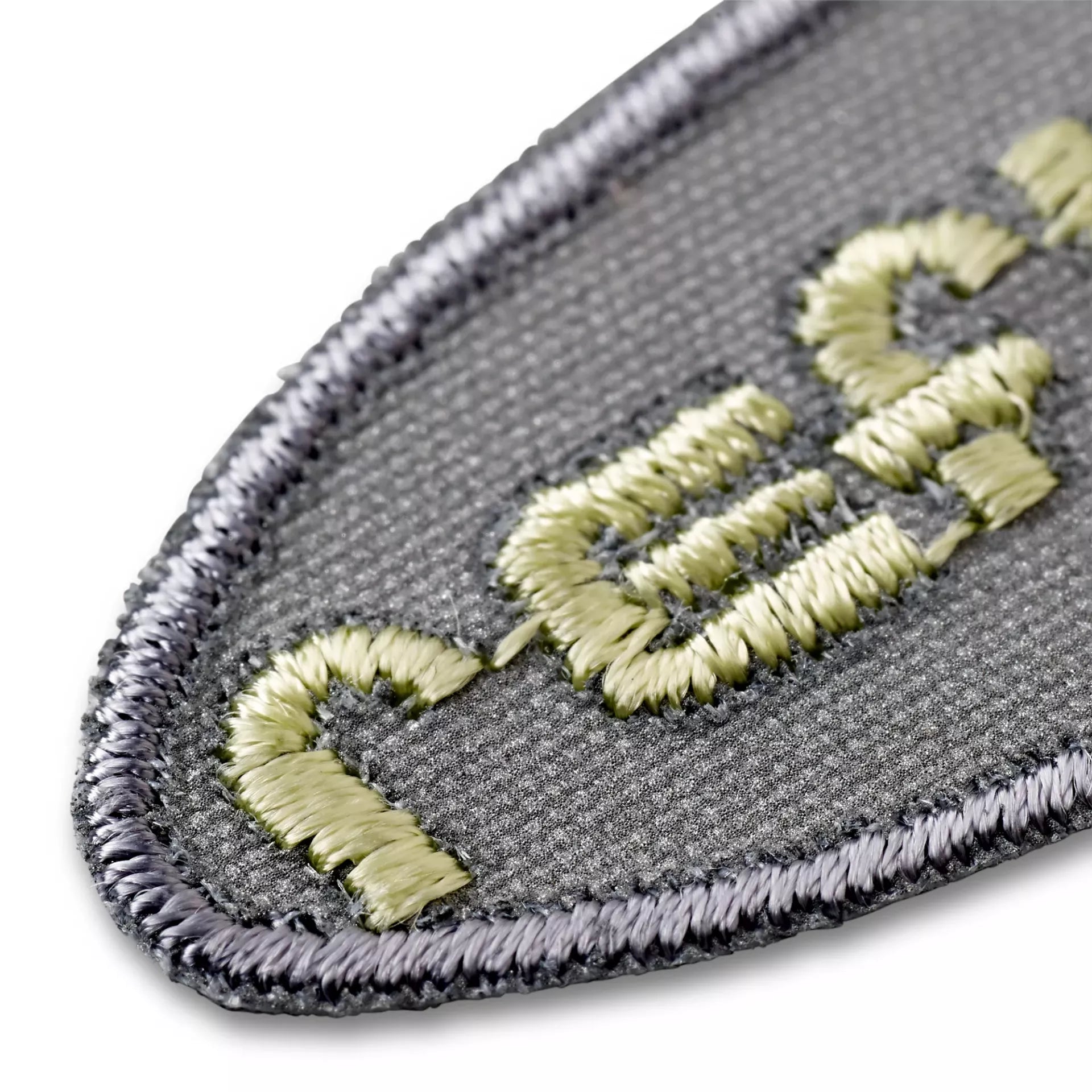 Close-up of a grey reflective self-adhesive and iron-on applique with embroidered yellow lettering.
