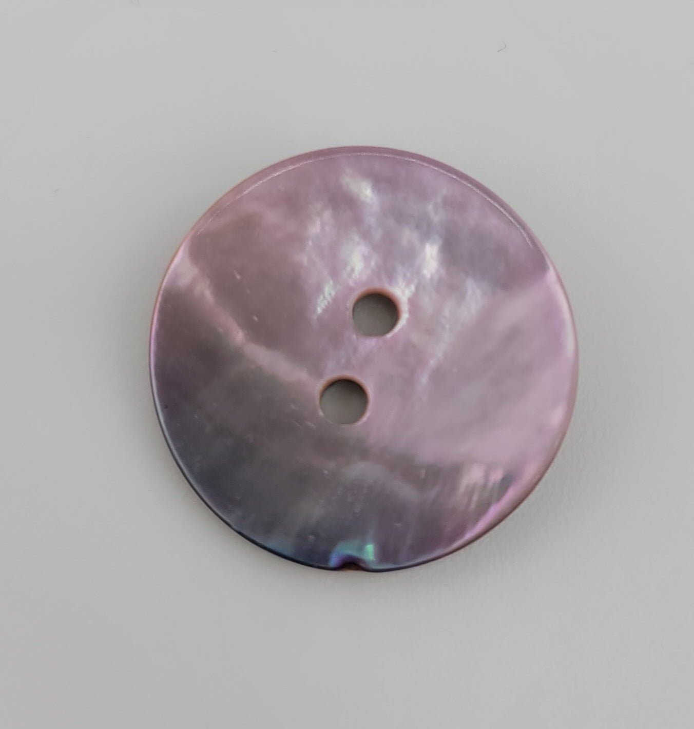 Round, iridescent pink shell button with two holes.