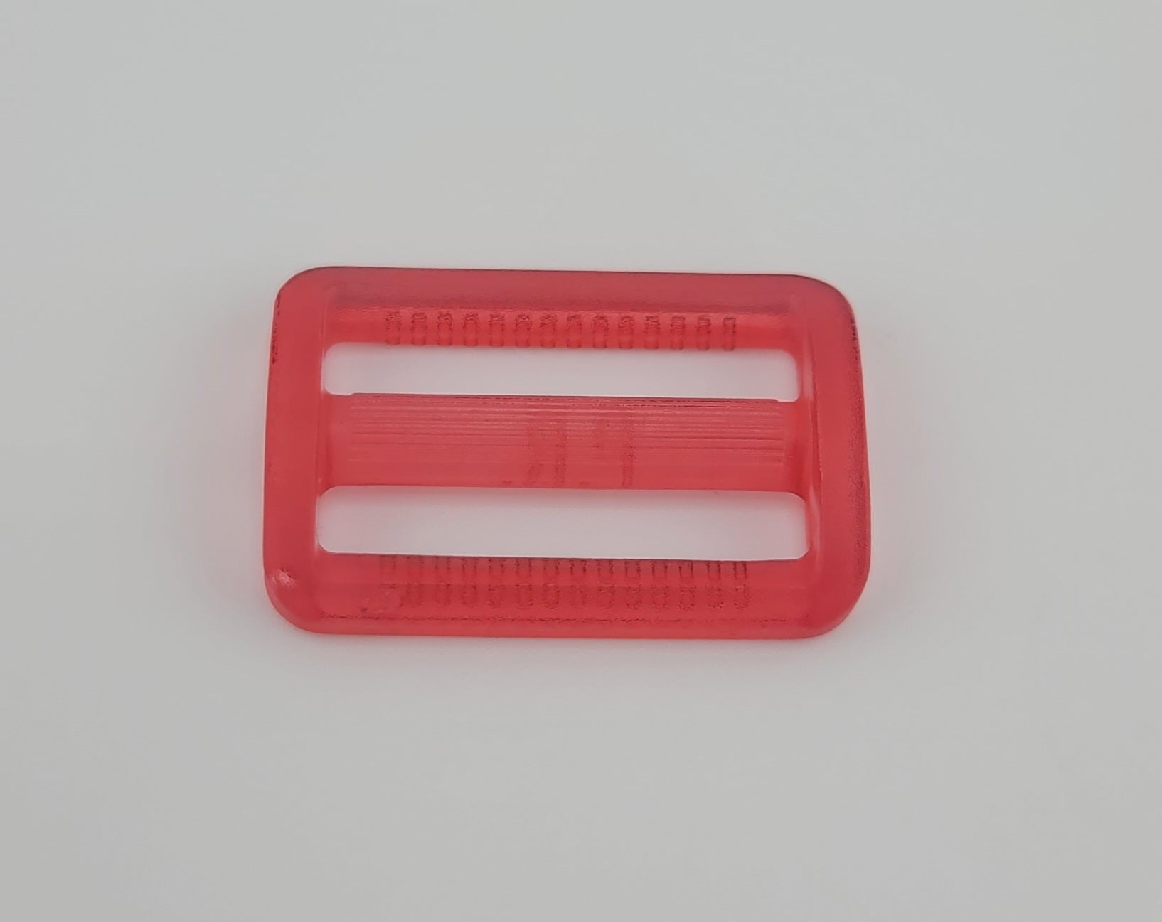 Red plastic 30mm adjuster buckle with three slots for sewing and crafting.