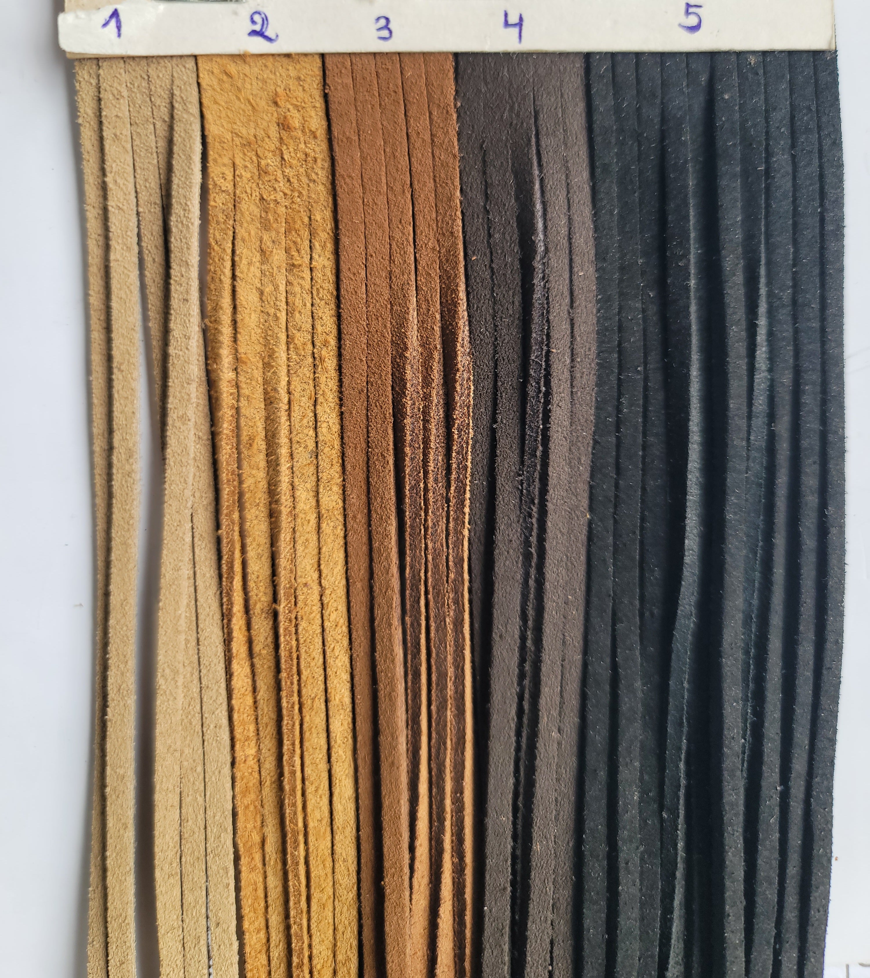 Five strips of suede ribbon in varying shades of tan, brown, and black.