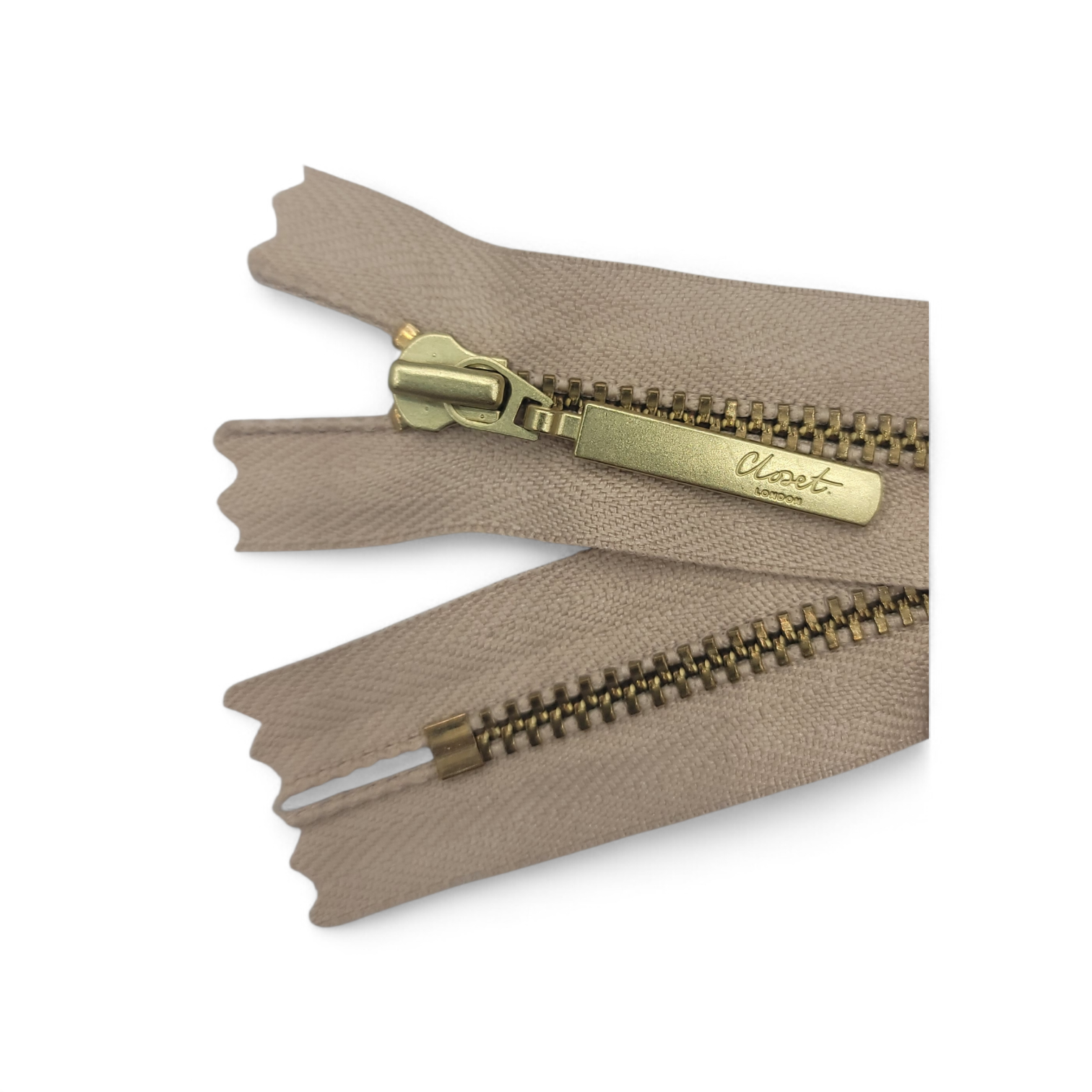 A beige YKK closed-end metal zipper with a gold pull tab.