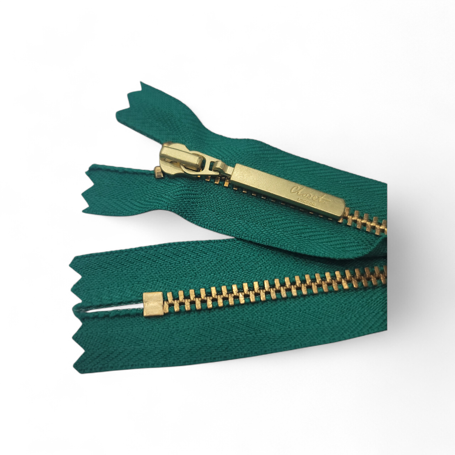 YKK Size 3 closed end gold metal zip with green fabric.