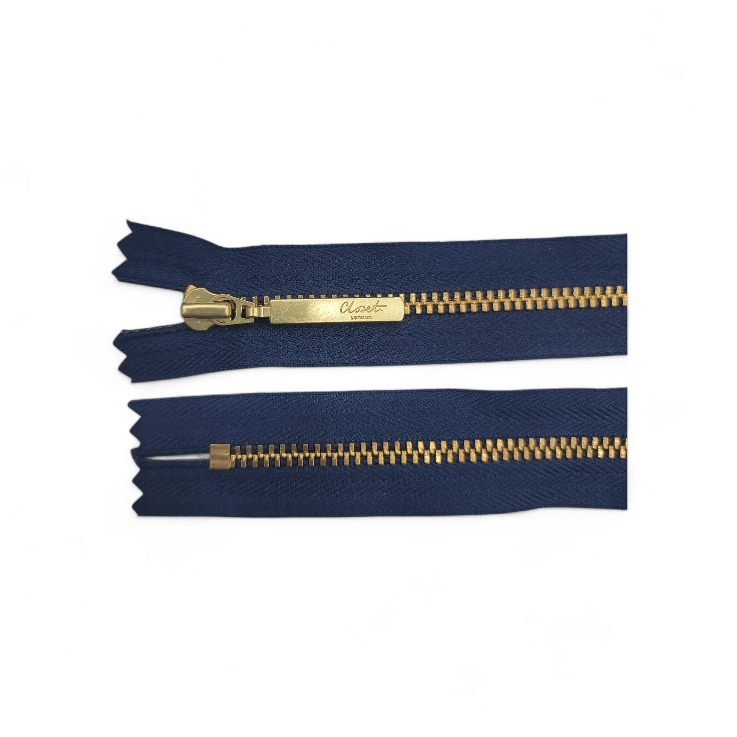 YKK size 3 closed end gold metal zipper on navy blue fabric.