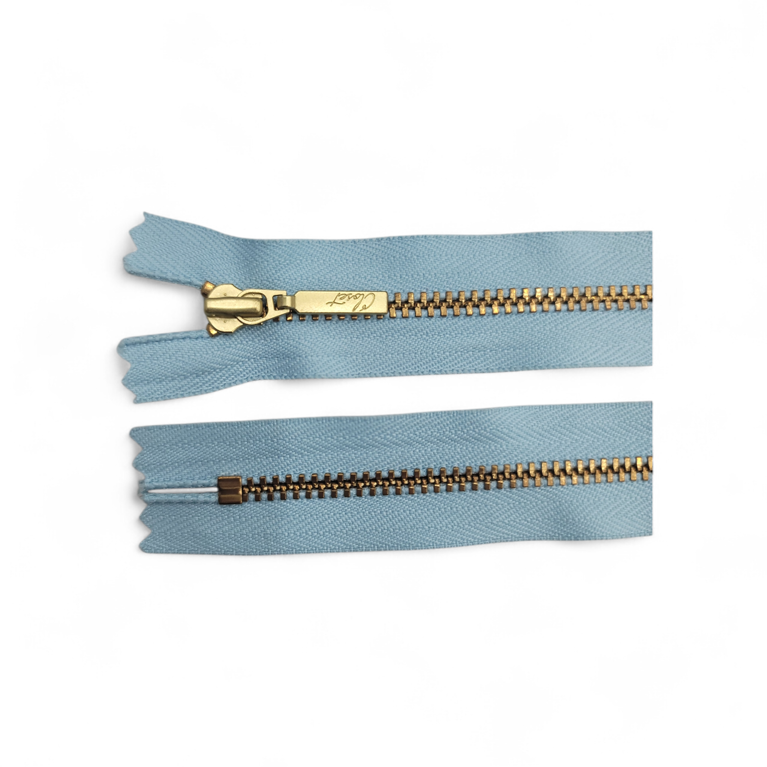 YKK size 3 closed end gold metal zipper on light blue fabric.