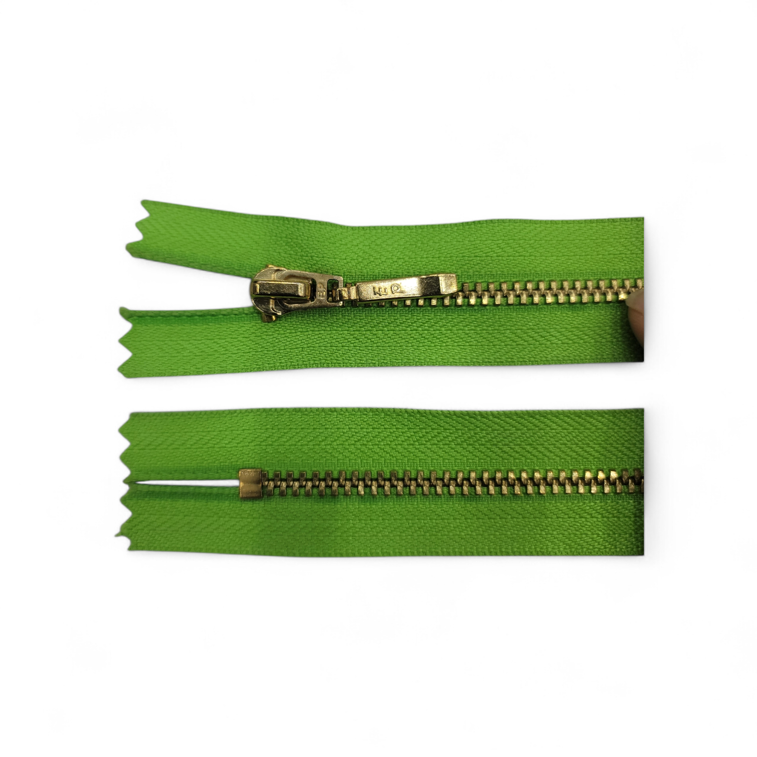 YKK size 3 closed end gold metal zipper on green fabric.