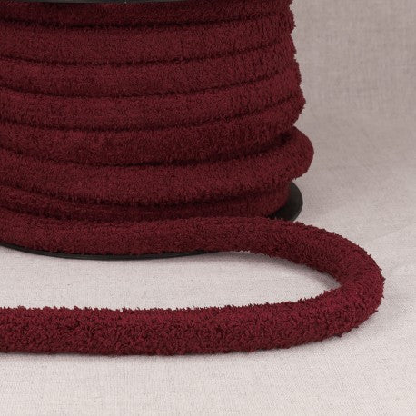 Maroon polyester cord with loops for bags on a spool.