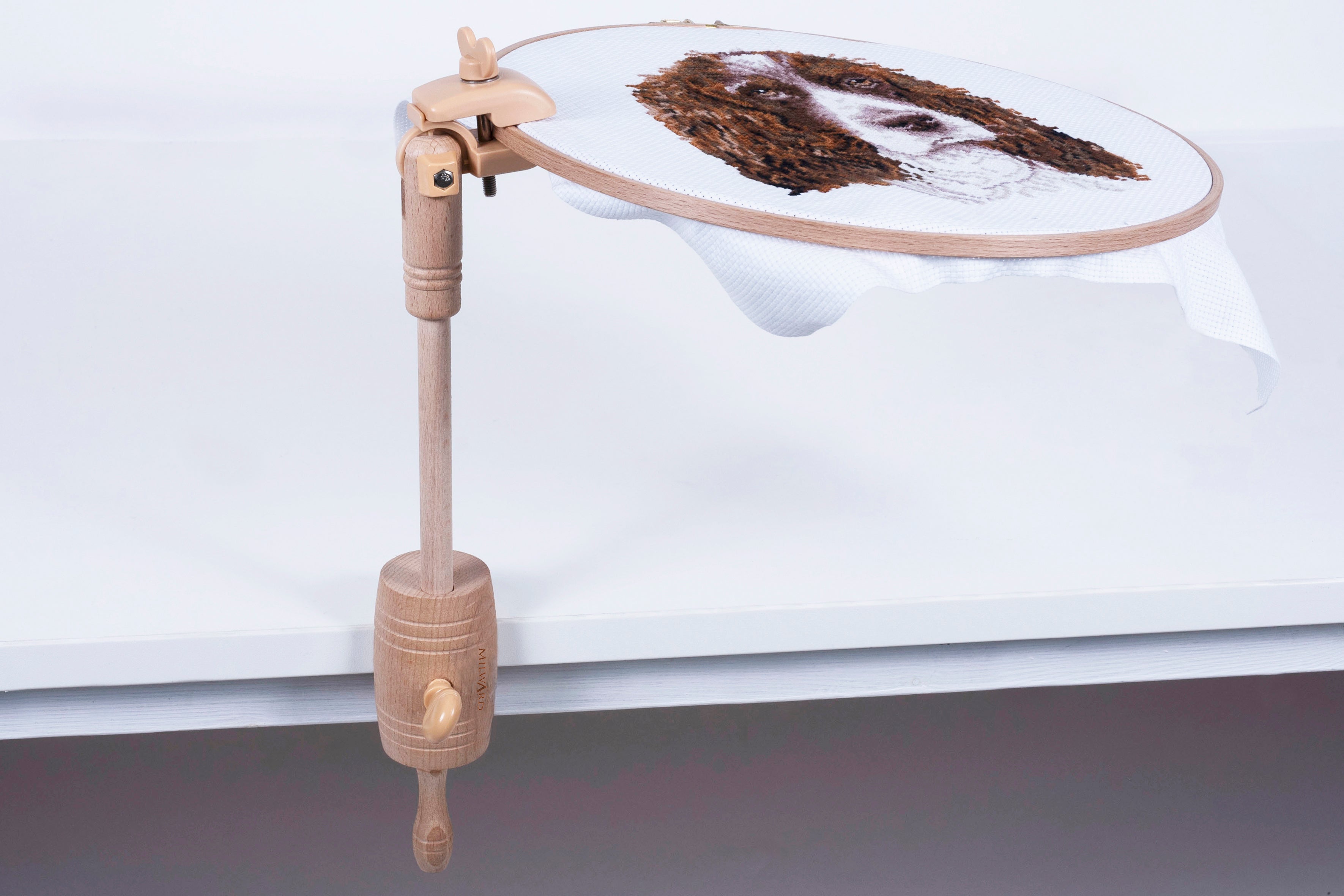 Milward beech wood table clamp holding an embroidery hoop with a dog portrait on a white table.
