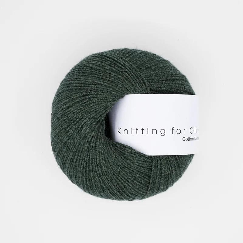 A ball of Knitting for Olive Cotton Merino yarn in Bottle Green with a white paper label.