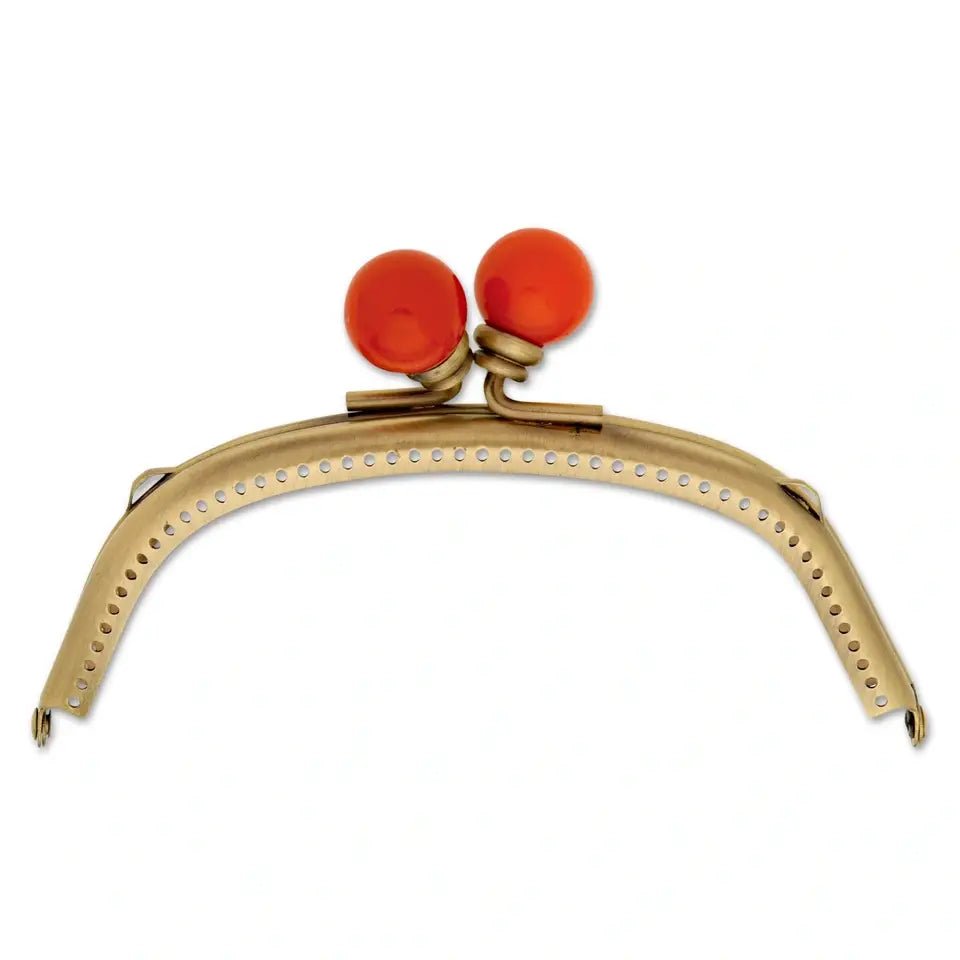 Antique brass bag fastening with two orange-red buttons.