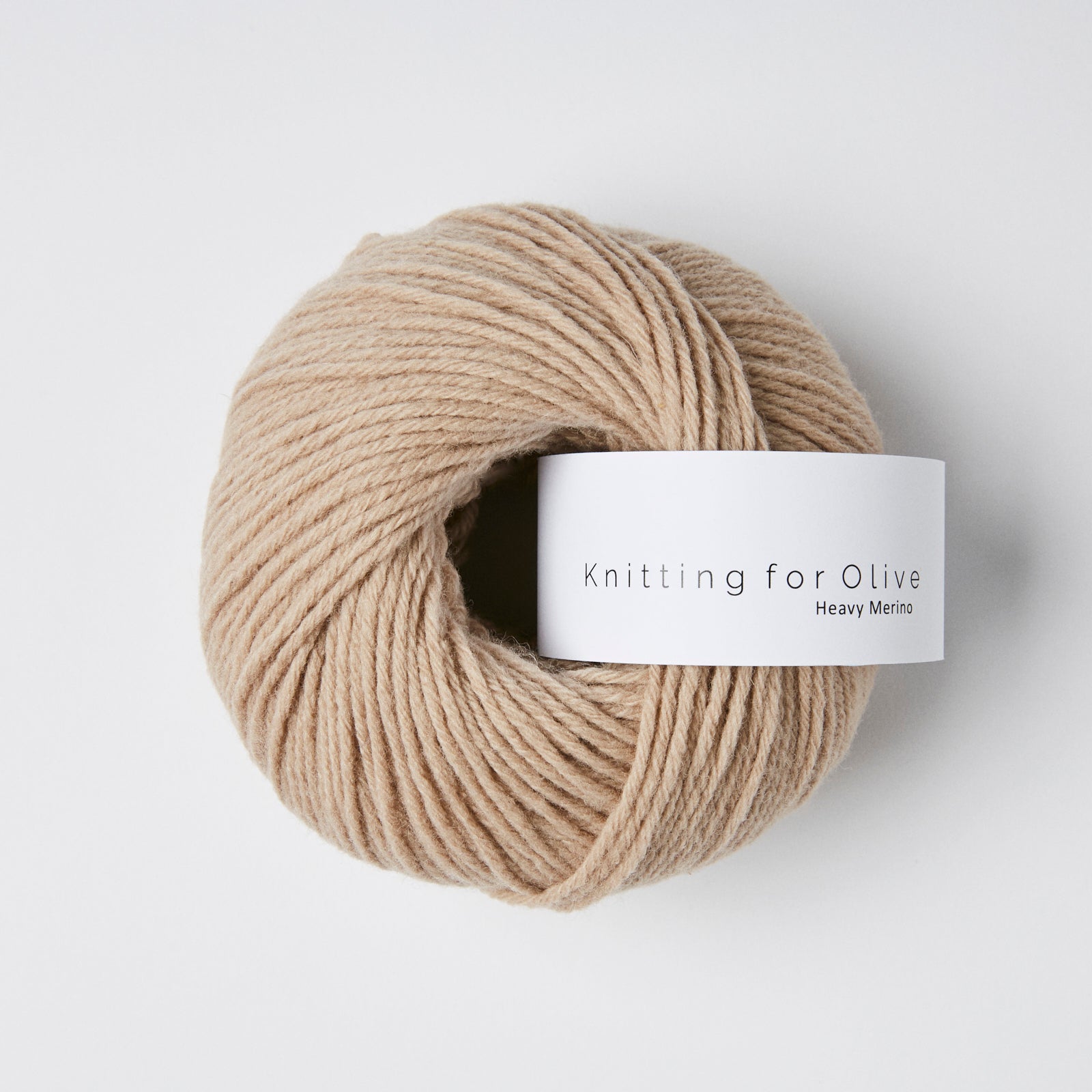 A ball of beige Heavy Merino yarn with a white label that reads "Knitting for Olive Heavy Merino".