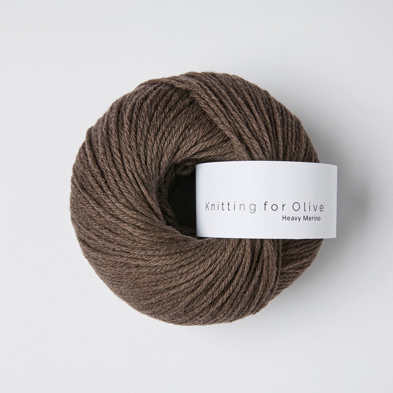 A ball of brown Heavy Merino yarn with a white label that says "Knitting for Olive Heavy Merino".