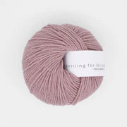 A ball of dusty rose heavy merino wool yarn with a white label.
