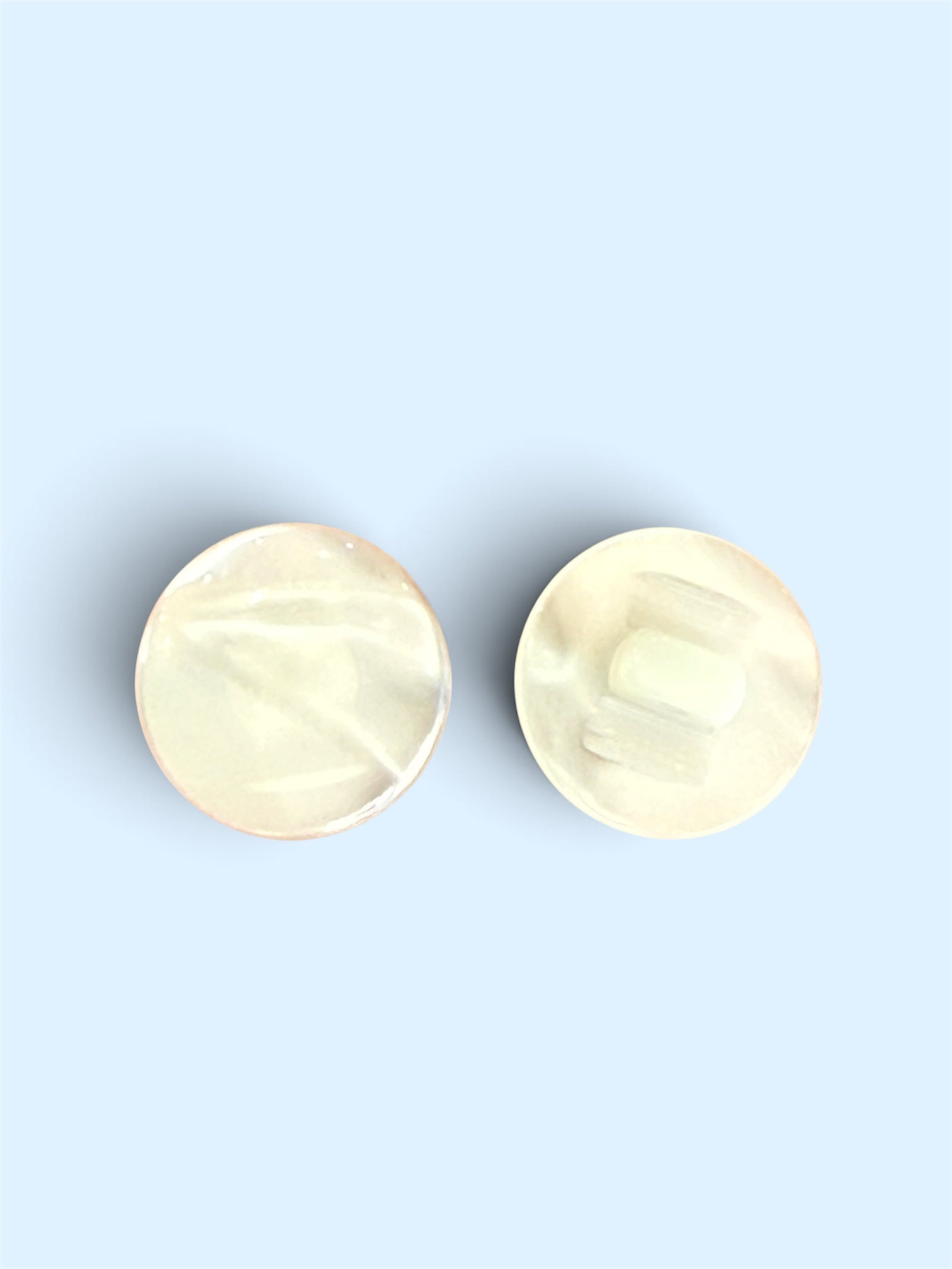 Two plain ivory resin sewing buttons with a flat profile shown from the front and back.