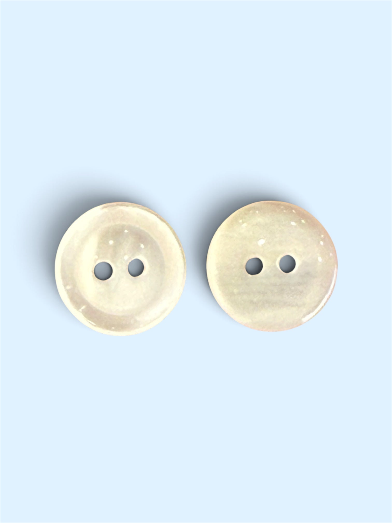 Two shiny ivory 2-hole sewing buttons in 14mm and 17mm sizes on a light blue background.
