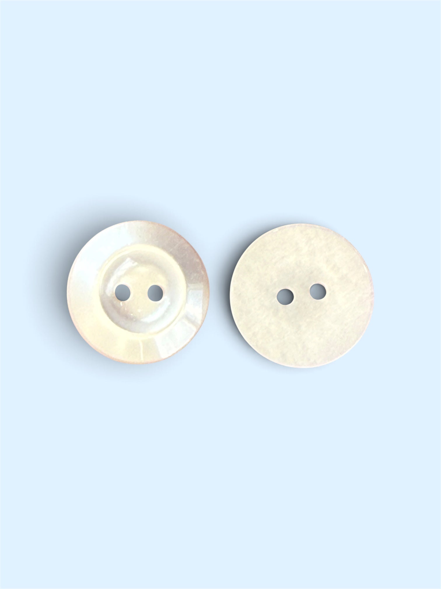 Two 19mm white resin buttons with a 2-hole flat back design on a light blue background.