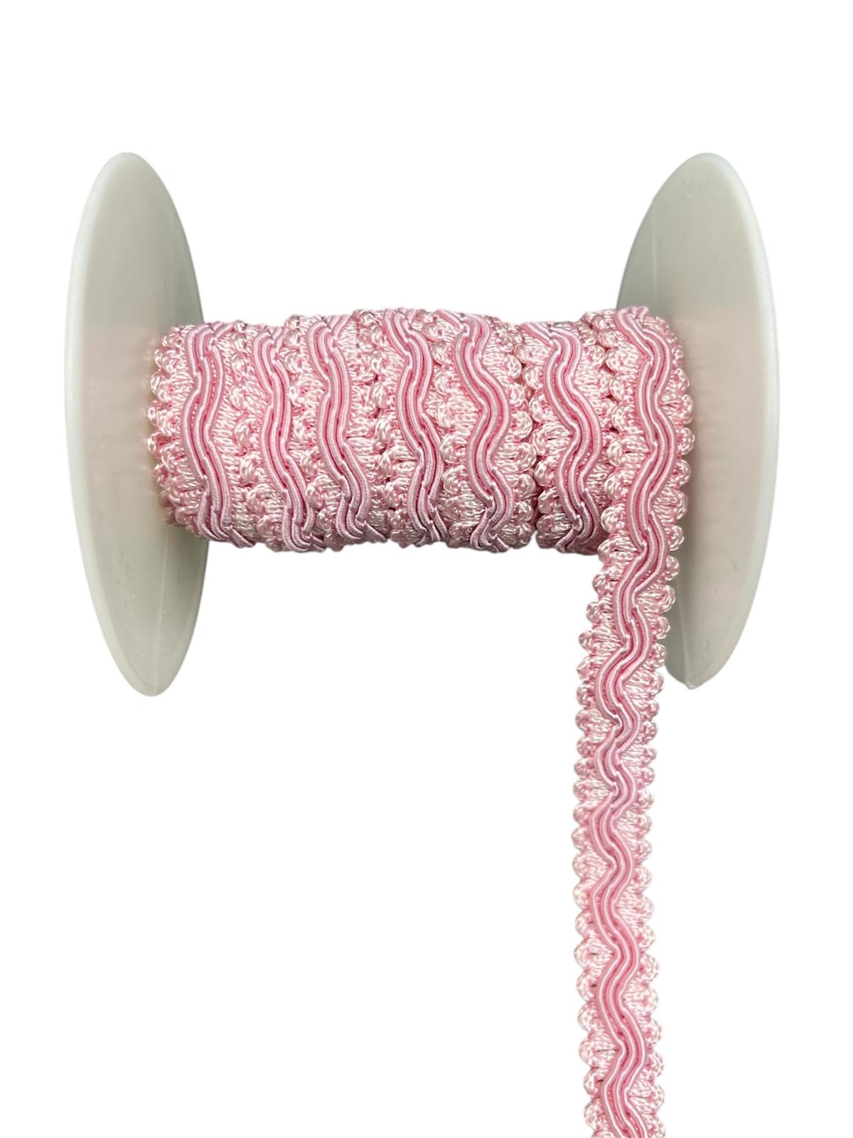 Pink decorative lace trim cord on a white spool.