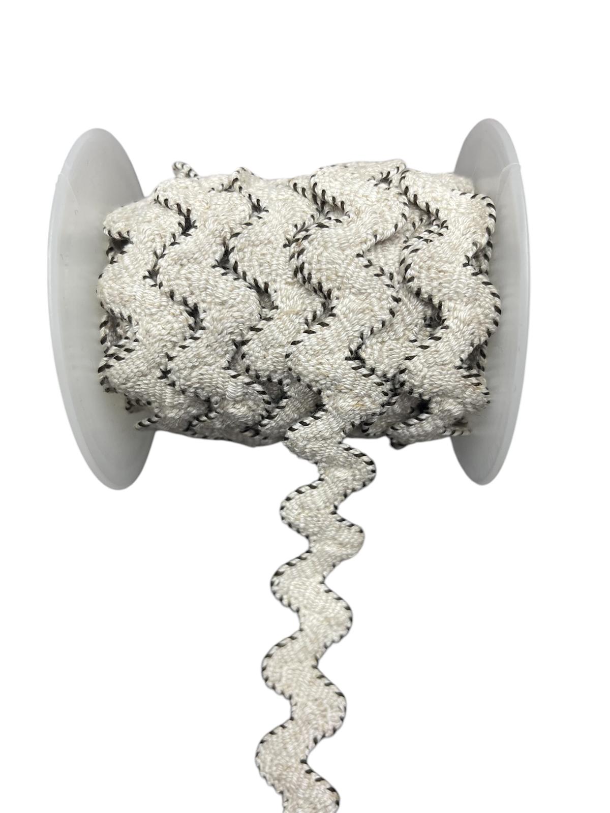 White and black decorative trim cord on a spool.