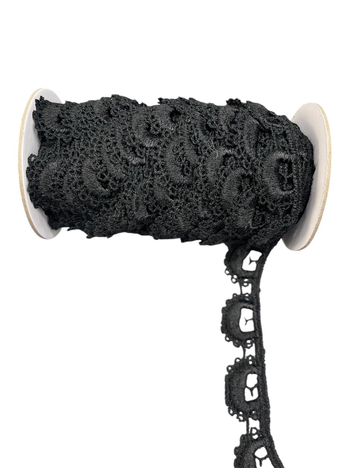 Black decorative lace trim cord on a spool with a scalloped edge.