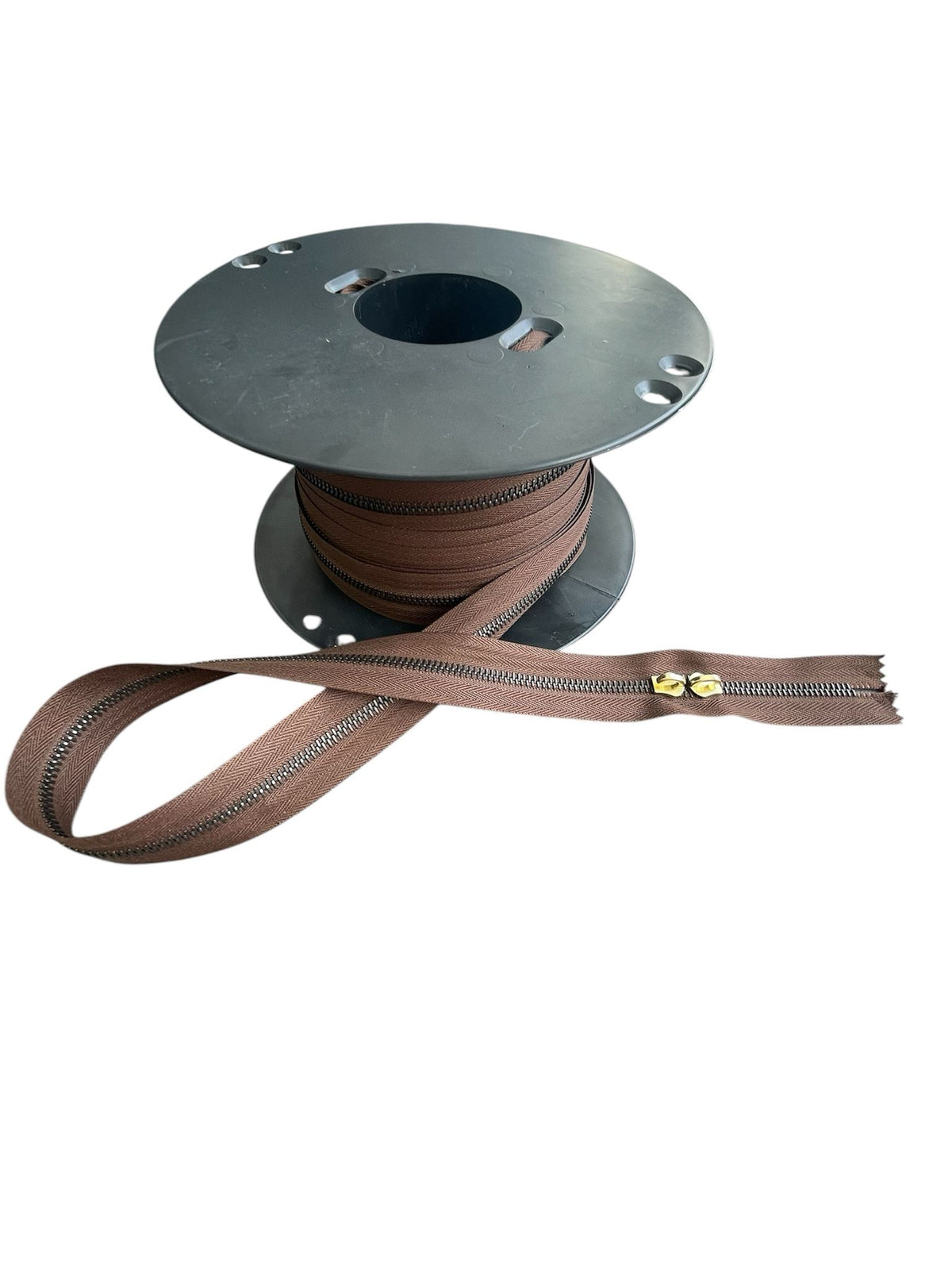 Riri M6 brown metal zipper on a spool with a pulled section.