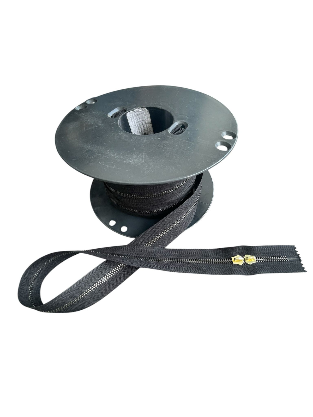 Riri M6 black metal continuous zipper on a spool with a portion unrolled.