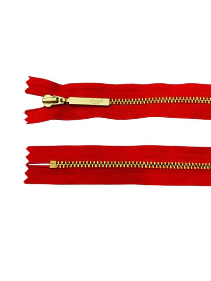YKK Size 3 closed end gold metal zipper on red fabric.