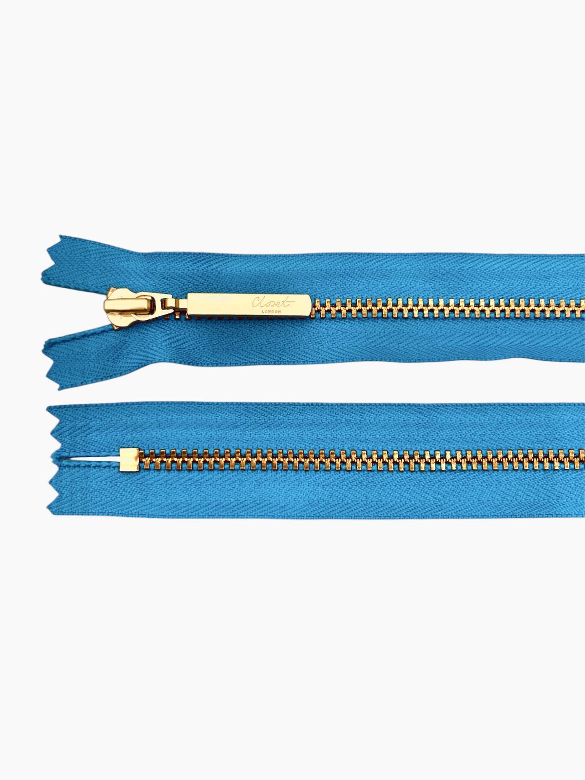 YKK size 3 closed end gold metal zipper on blue fabric.