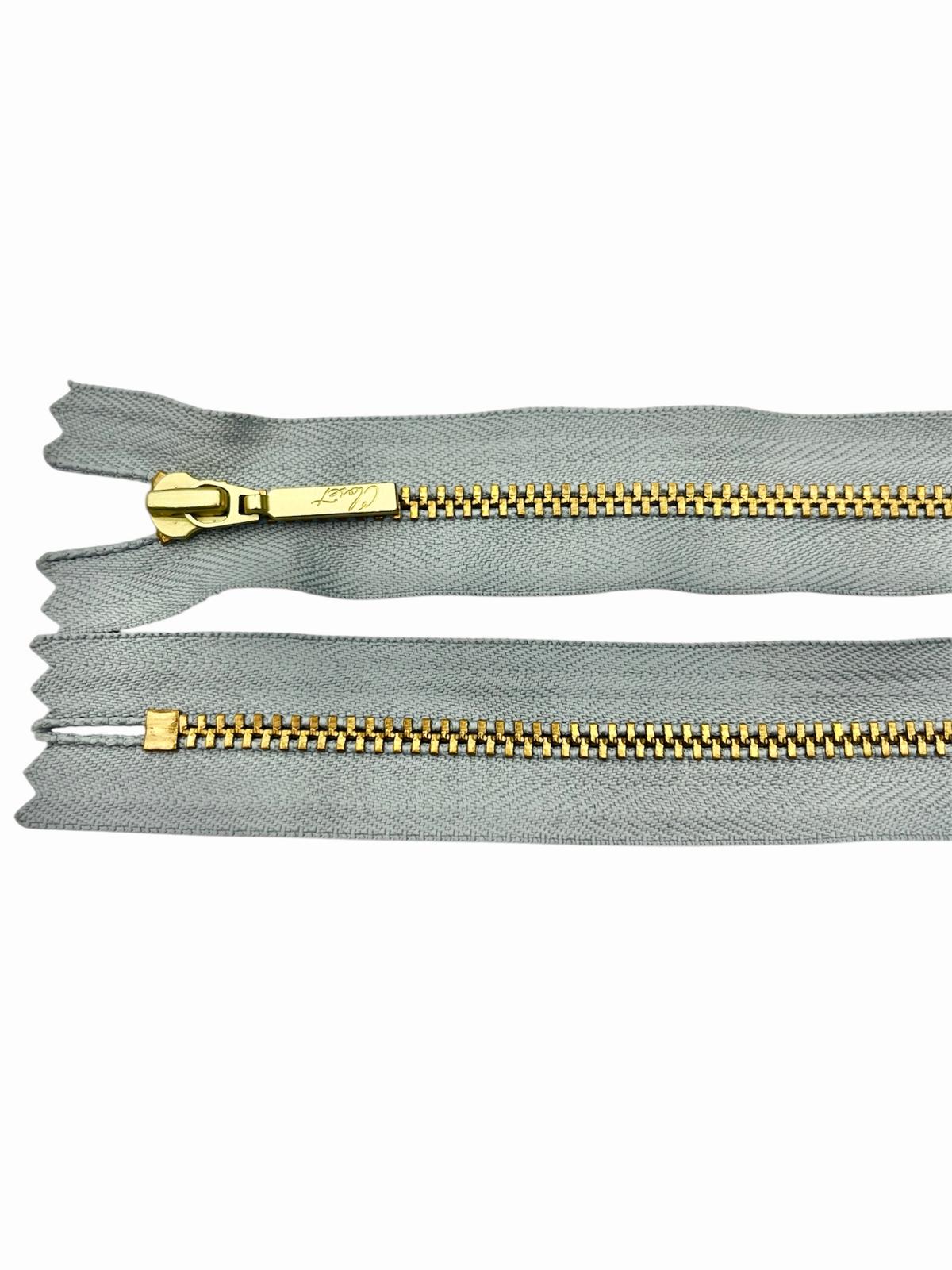 YKK size 3 closed end gold metal zipper on grey fabric.