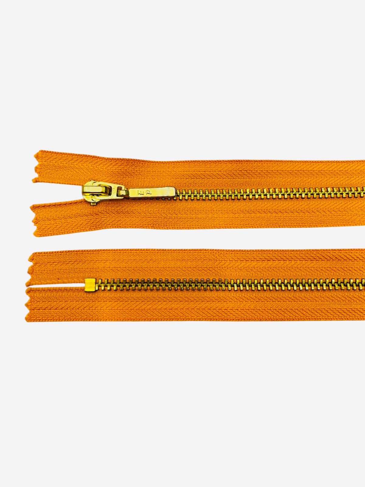 YKK size 3 closed end gold metal zipper with orange fabric.