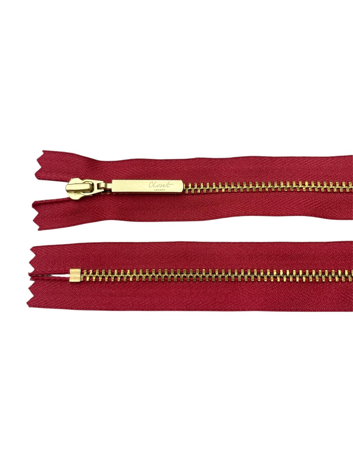 YKK size 3 closed end gold metal zipper on red fabric.