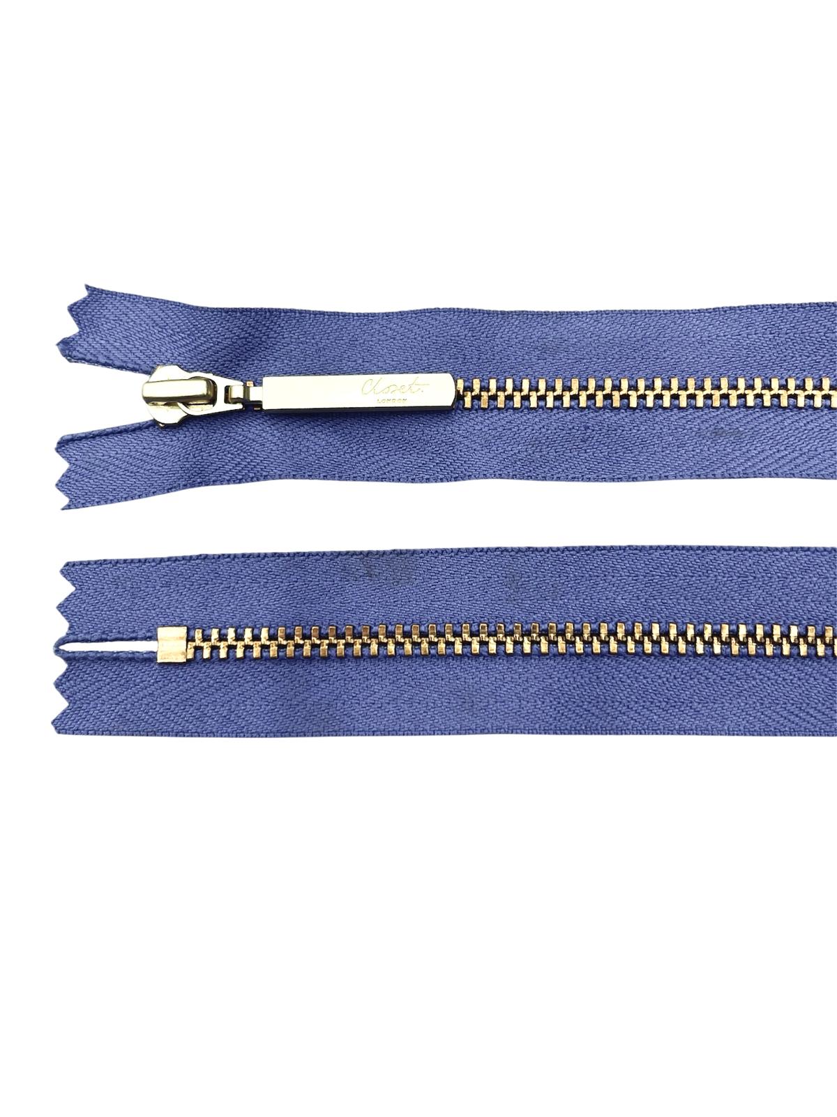YKK size 3 closed end gold metal zipper with blue fabric.