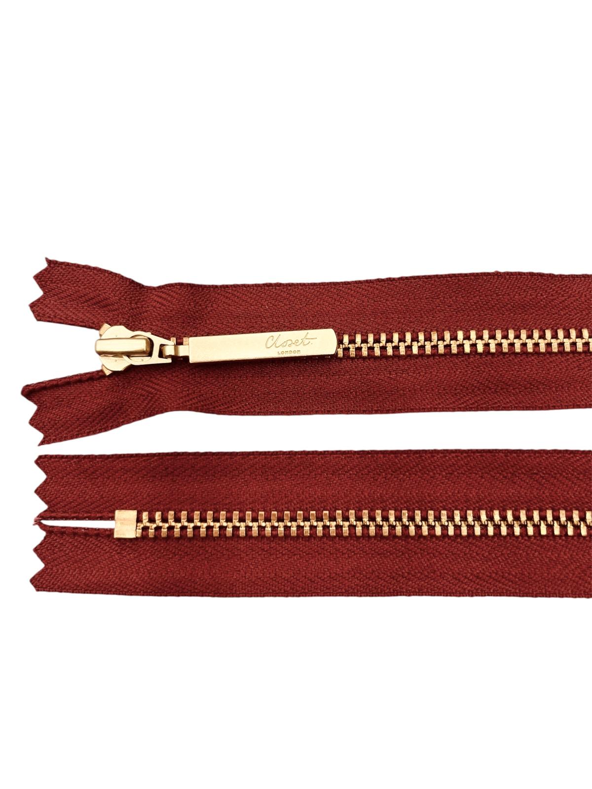 YKK size 3 closed end gold metal zipper on red fabric.