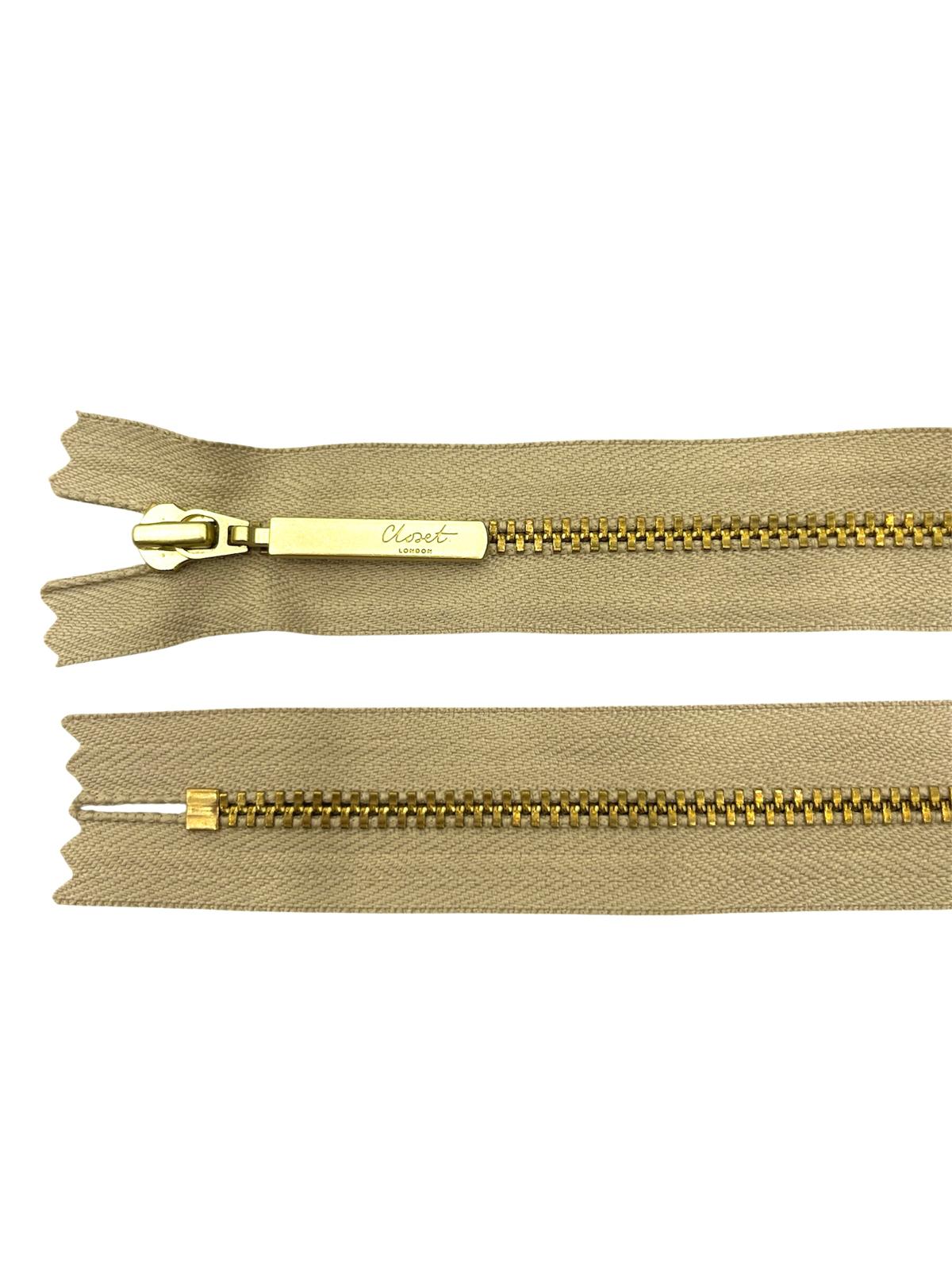 YKK Size 3 closed end gold metal zipper with beige tape.