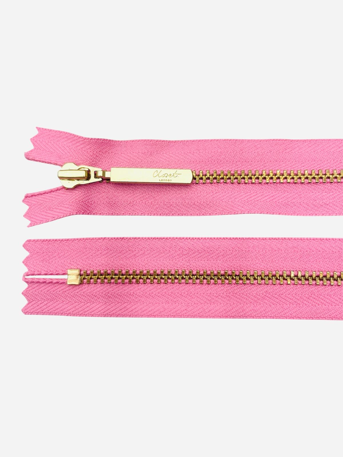 YKK size 3 closed end gold metal zip on pink fabric.