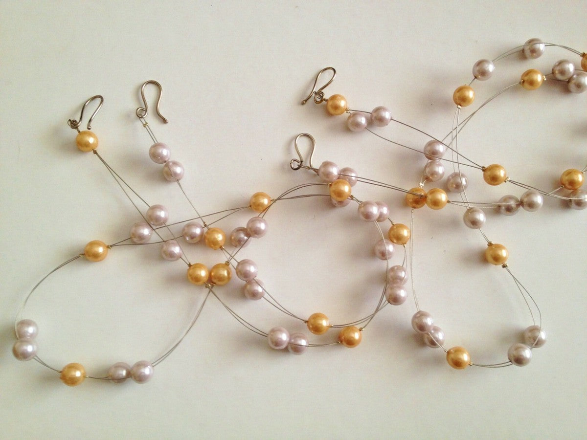 Multi-strand wired curtain tie backs featuring ivory and gold faux pearls with metal hook ends.