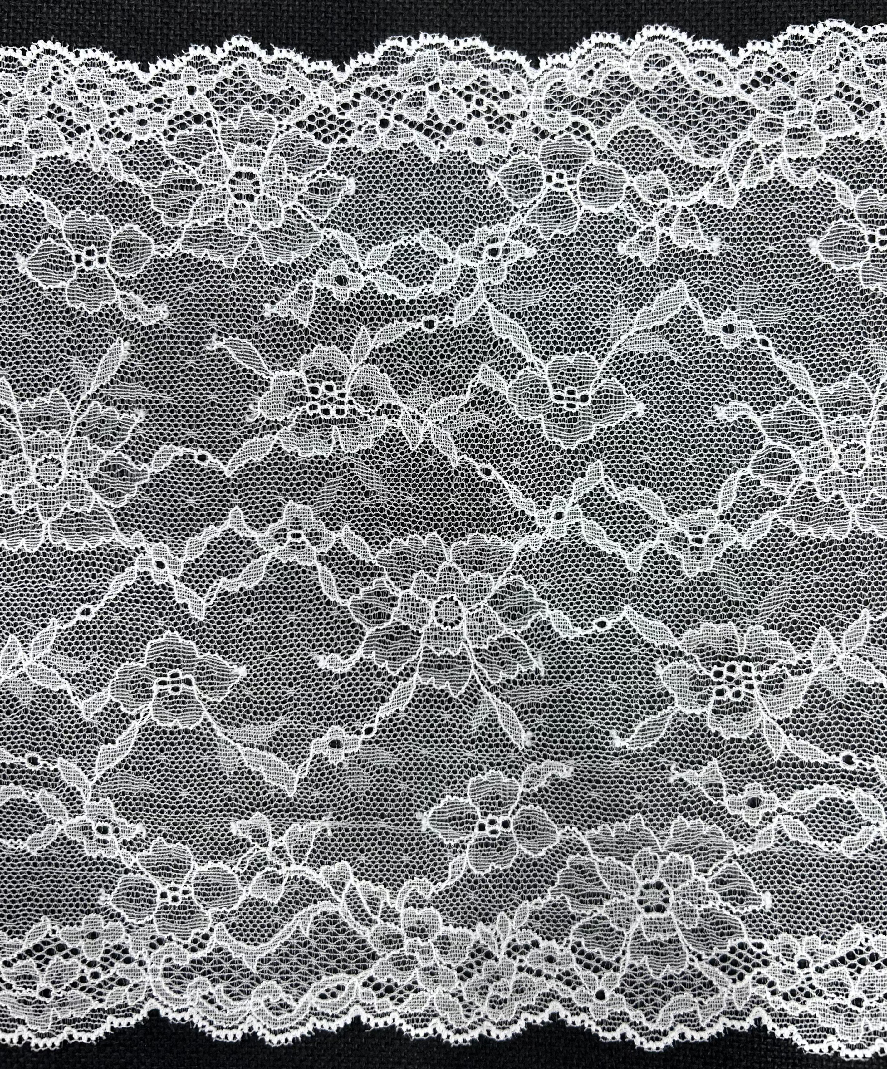 White floral lace trim with a scalloped edge on a black background.