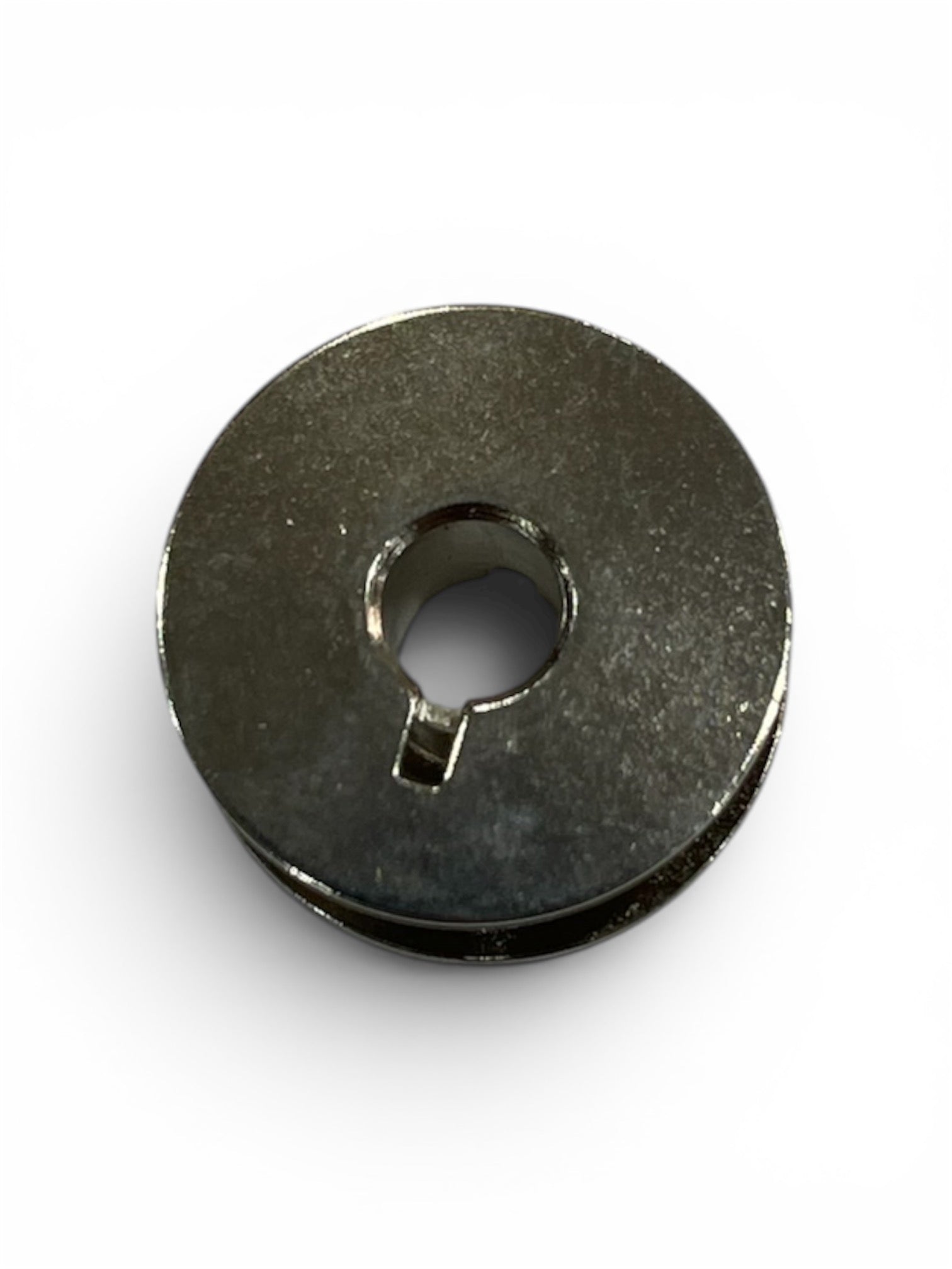 Top view of a single Janome Class 15 universal metal bobbin for domestic sewing machines.