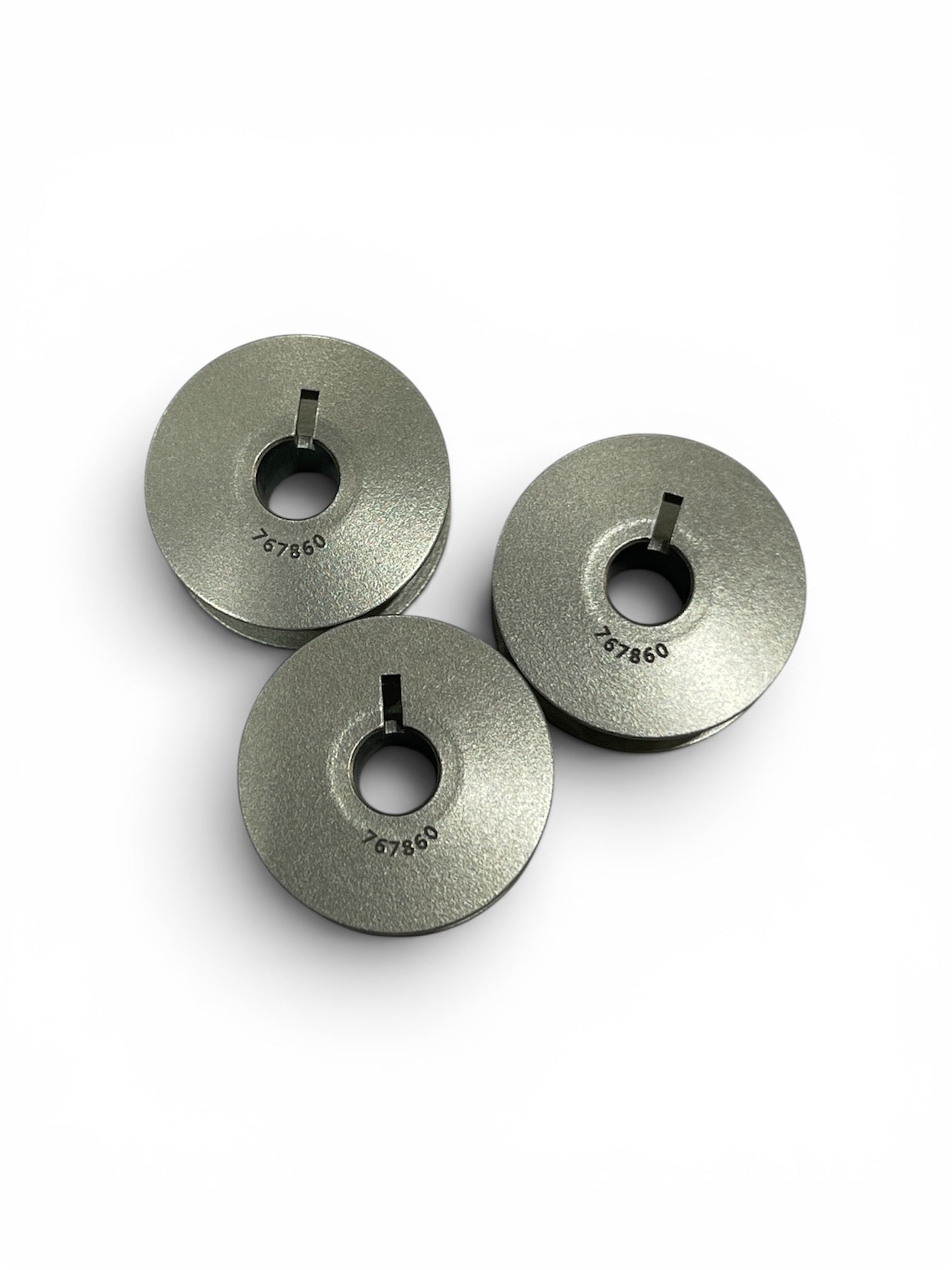 Three genuine Janome HD9 V2 jumbo metal bobbins with part number 767860 engraved on the surface.