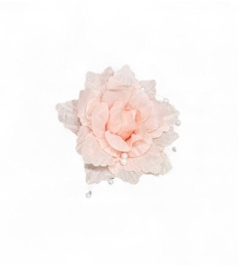 A light pink fabric flower with pearl accents on a white background.