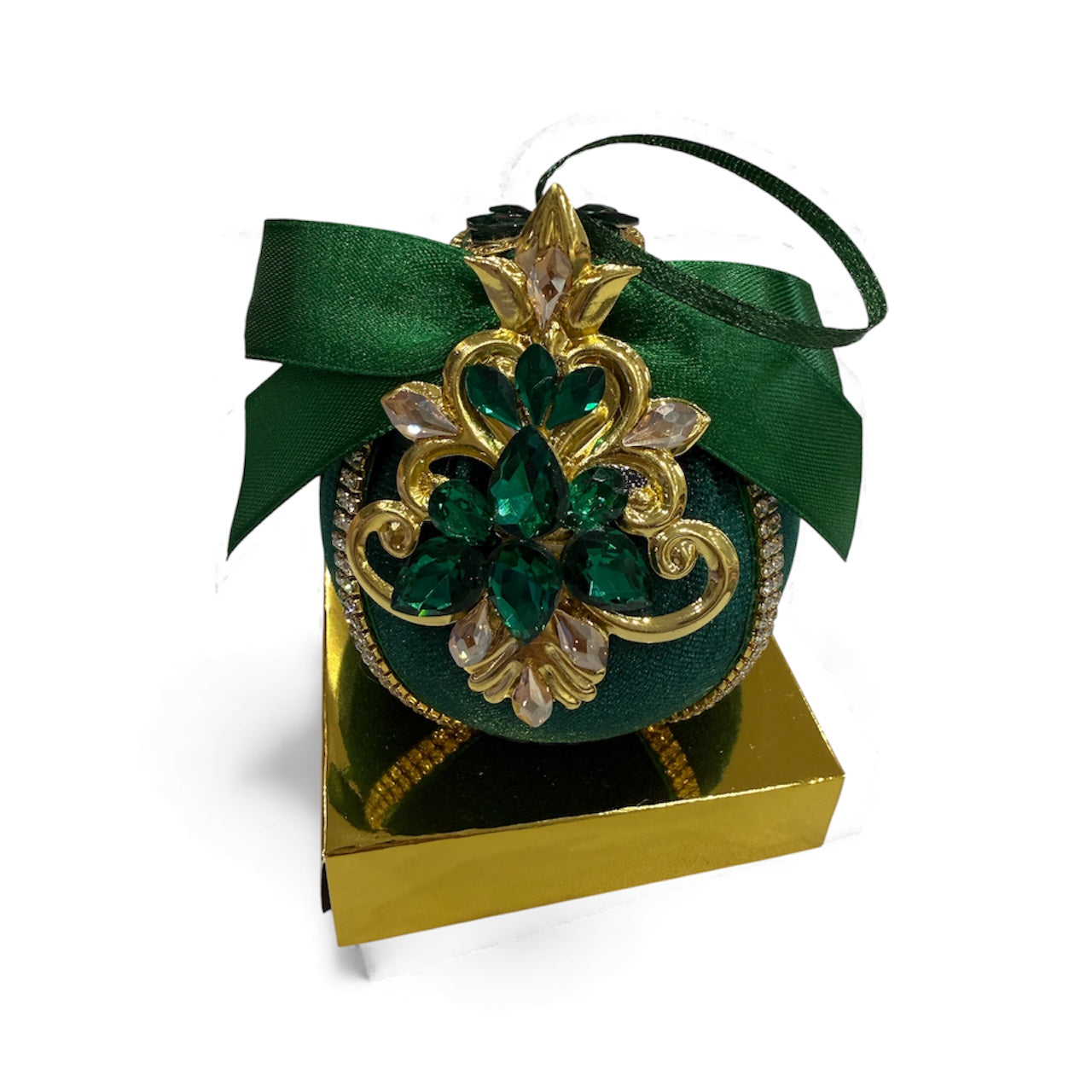 Green Christmas ornament with gold and emerald jewel embellishments on a gold box.
