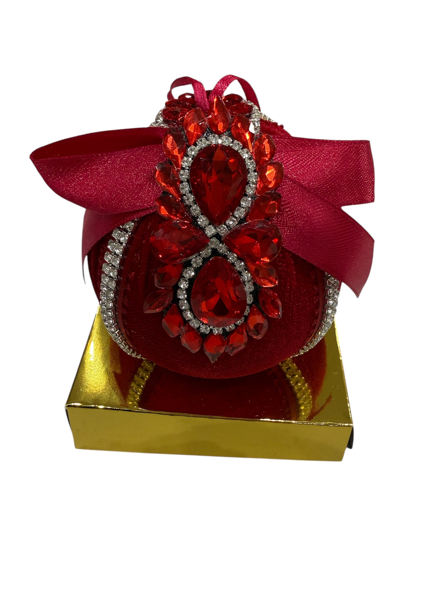Red round Christmas ornament with red jewels and a gold box.