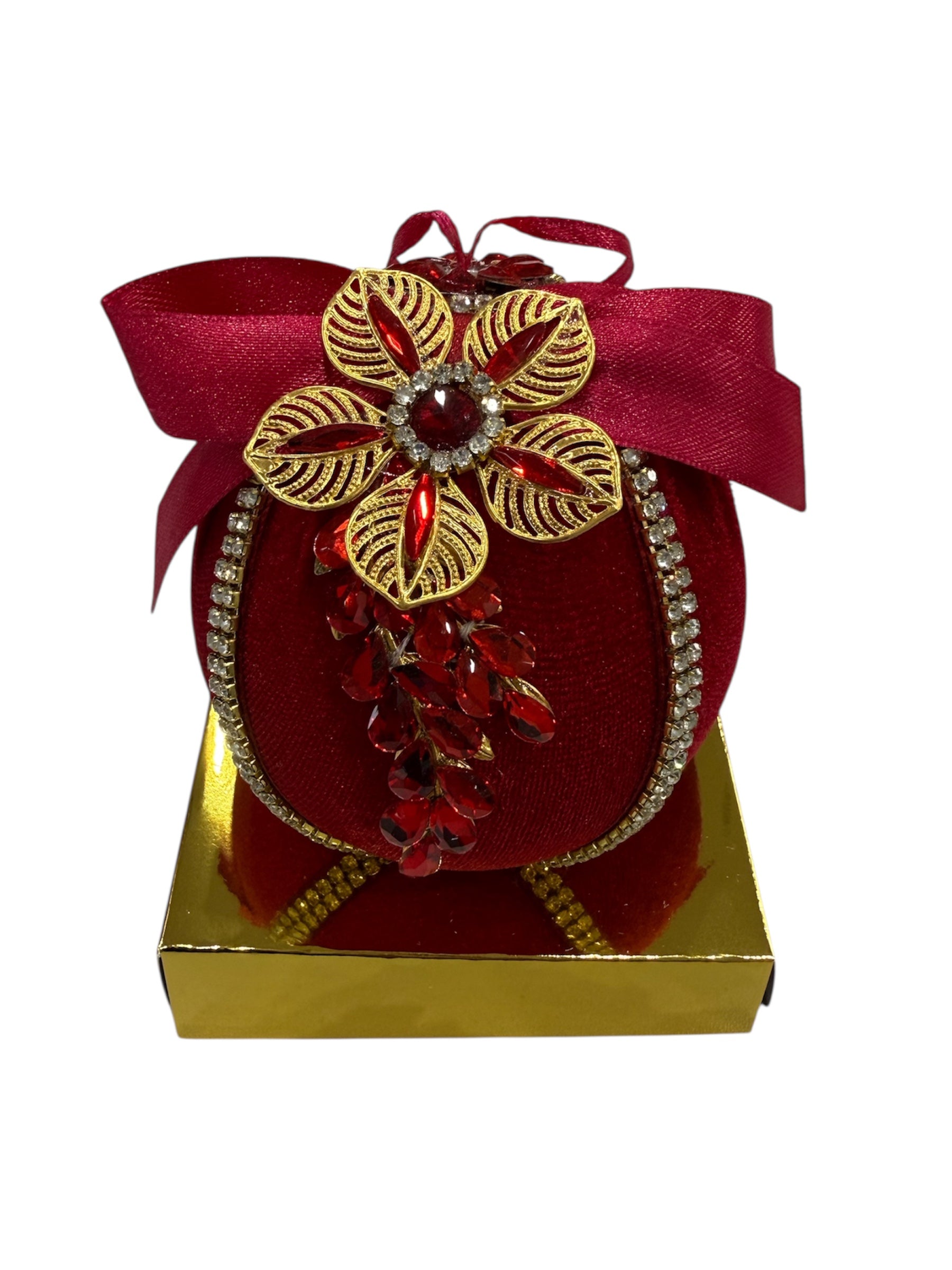 Red round decorative item with gold flower and red jewels on a gold base.