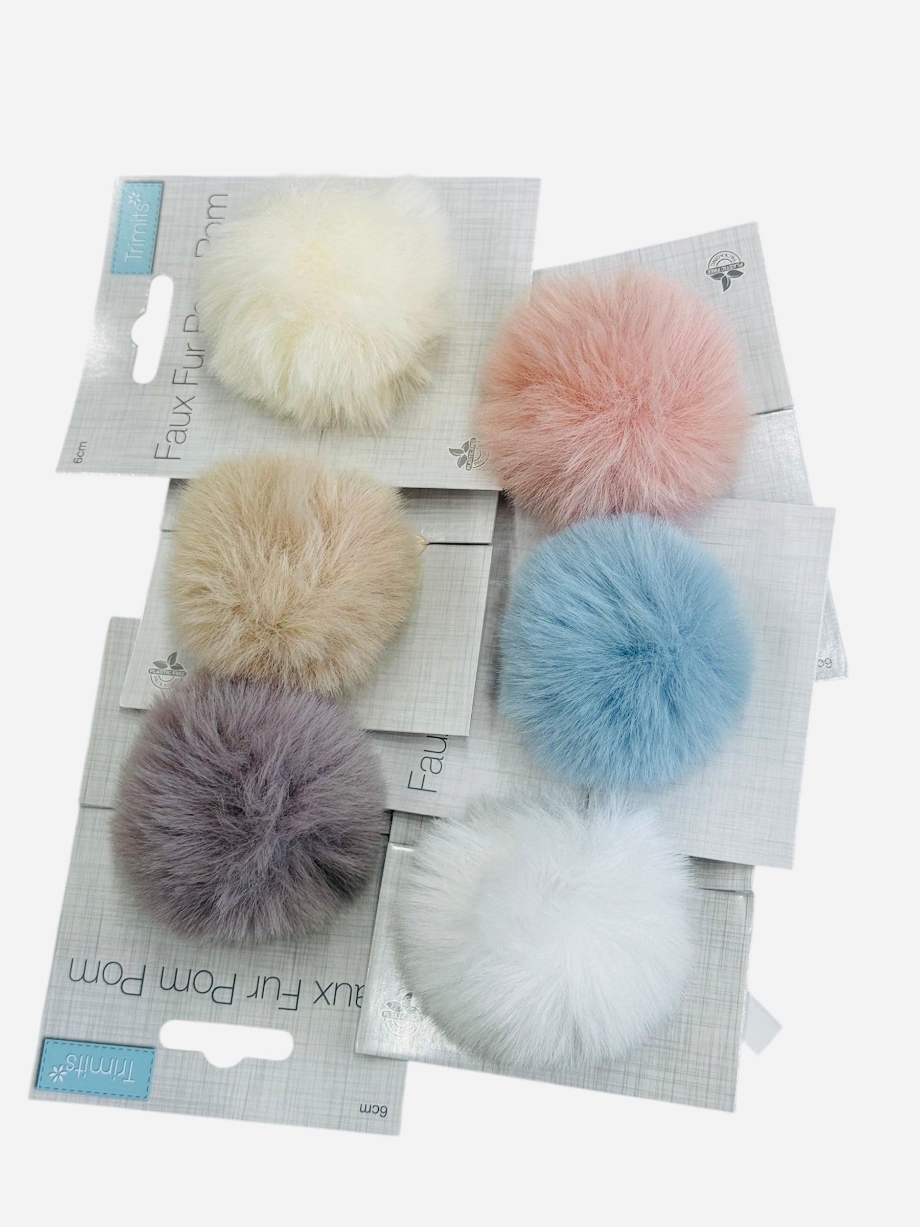 Six faux fur pompons in various pastel colors on packaging.