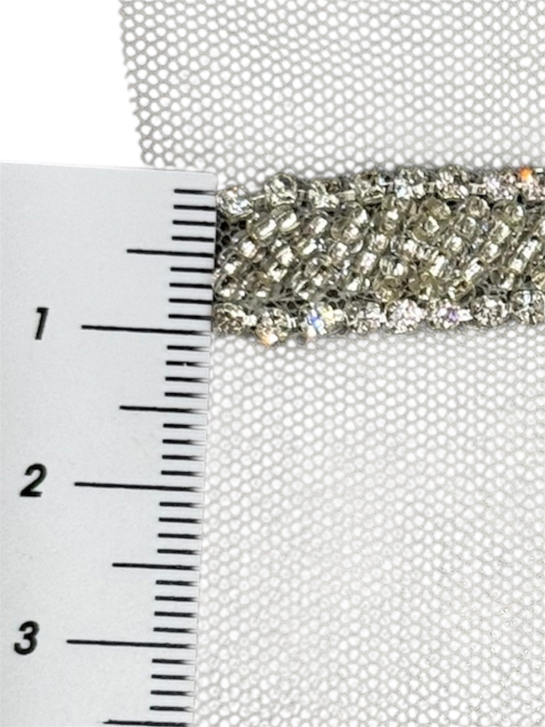 Silver embroidered fabric trim with rhinestones on a white mesh background, measured with a ruler.