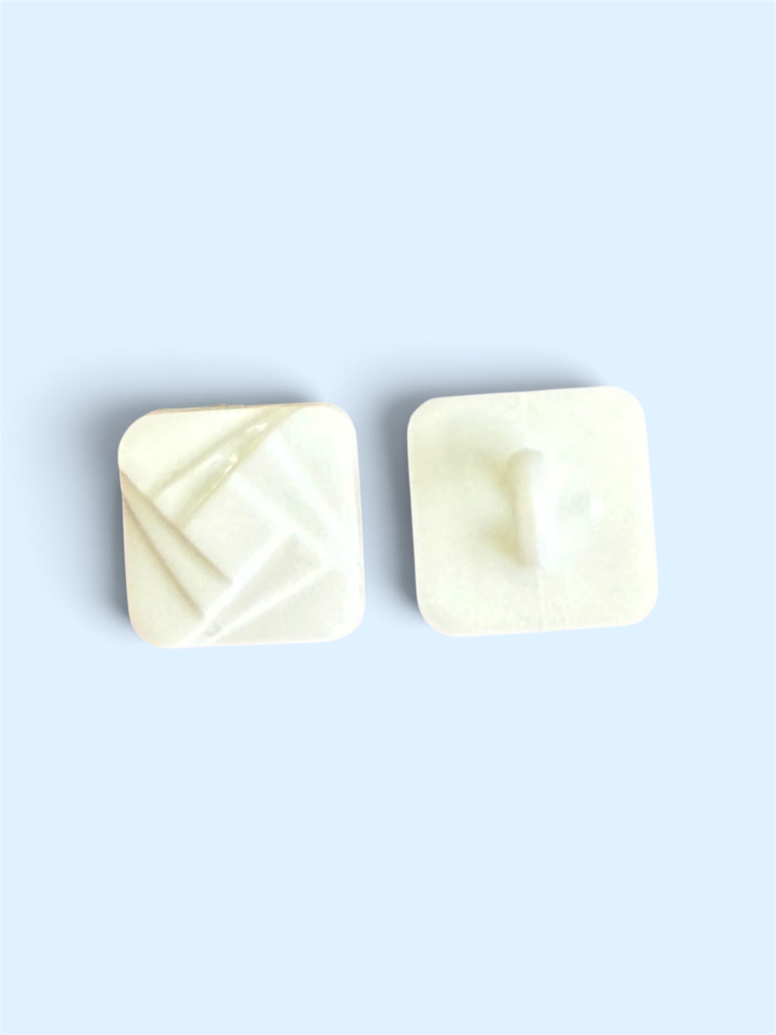 Two 12mm white square buttons with a textured geometric pattern and a shank back.