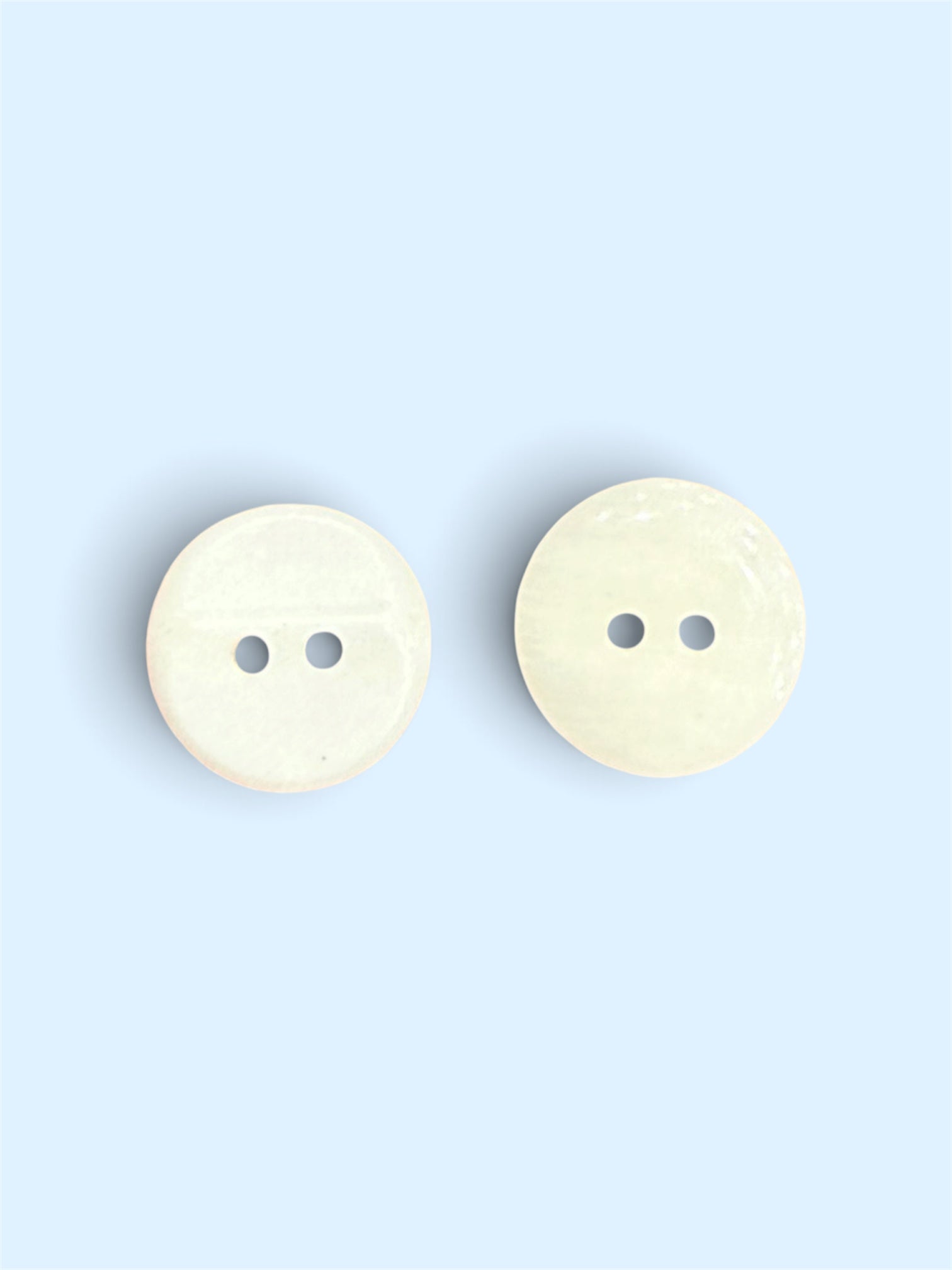 Two 15mm ivory resin buttons with a flat back and two-hole design.