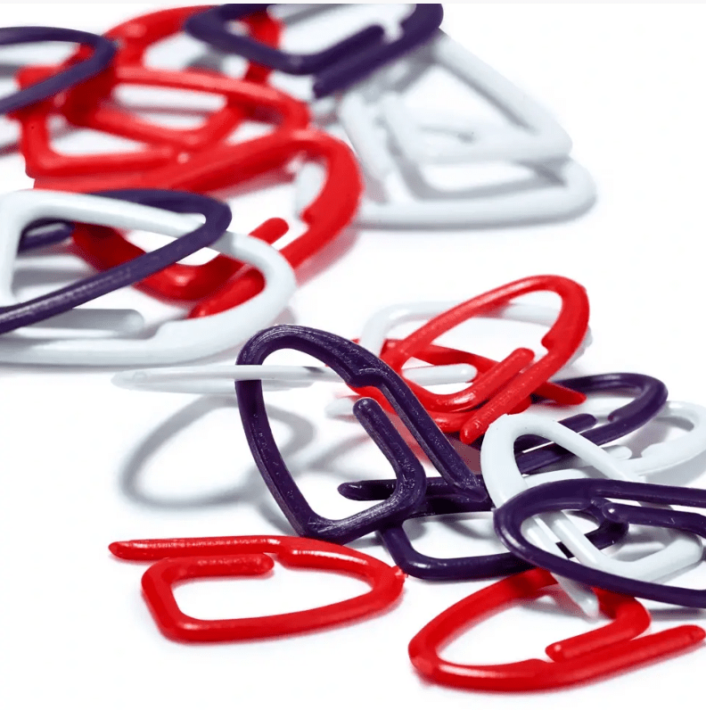 Prym stitch markers in assorted red, white, and plum blue plastic clips for knitting.